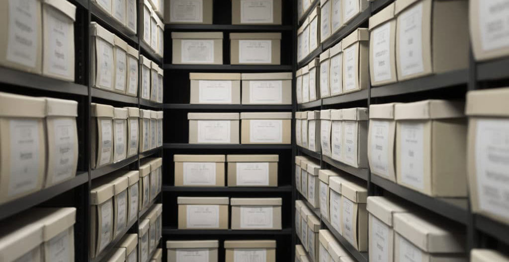 Une femme freelance déposant des cartons d'archives professionnelles dans un box de stockage bien rangé et éclairé