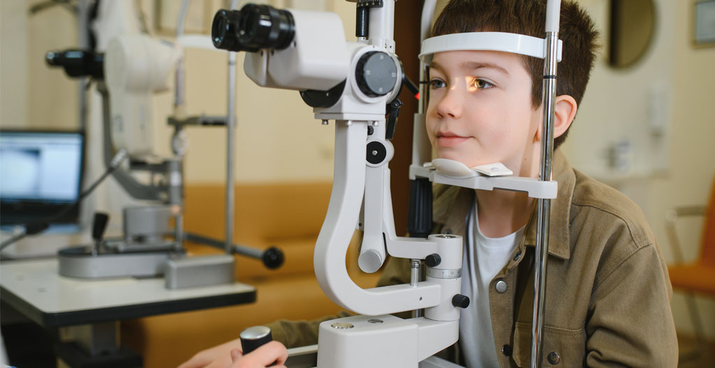 Enfant de 5 ans examiné au réfractomètre automatique pédiatrique par un ophtalmologue dans un cabinet médical