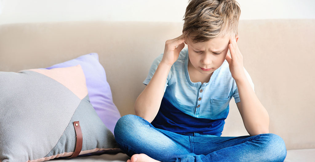 Enfant de 6 ans se frottant les yeux avec fatigue lors d'une activité de lecture à son bureau de classe élémentaire